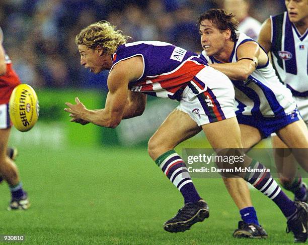 Shaun McManus for Fremantle hand balls while being tackled by Shannon Grant for the Kangaroos, in the match between the Kangaroos and the Fremantle...