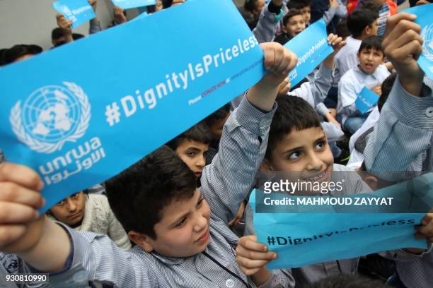 Palestinian refugees hold placards at a school belonging to the United Nations Relief and Works Agency for Palestinian Refugees in the town of...