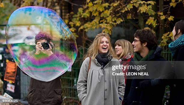 Man takes a photograph through a bubble in Mauer Park in central Berlin, on November 8, 2009. Germany is celebrating the 20th anniversary of the fall...