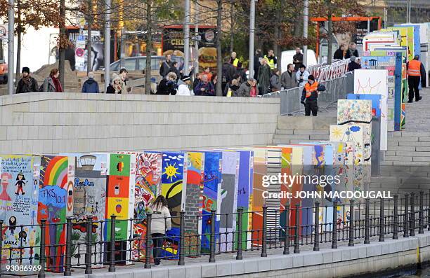 Visitors look at a row of giant dominos placed along the path of the former Berlin wall as part of celebrations marking the 20th anniversary of the...