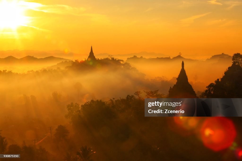 Sunset dramatic blue, orange, yellow, red sky with a silhouette view of Buddhist pagoda in Mrauk U, Rakhine, Myanmar