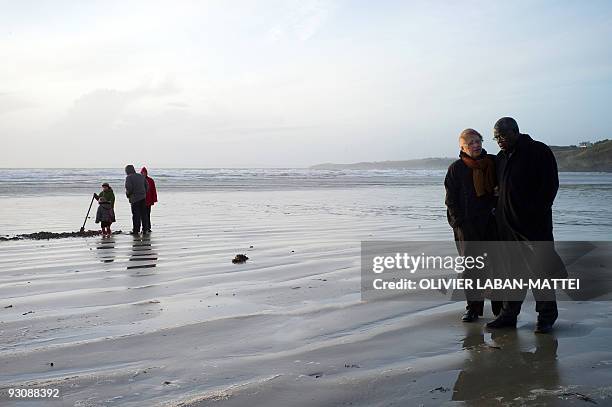 Franco-Togolese dual national politician Kofi Yamgnane walks with his wife Anne-Marie on the beach of Saint-Nic, western France, on November 14,...