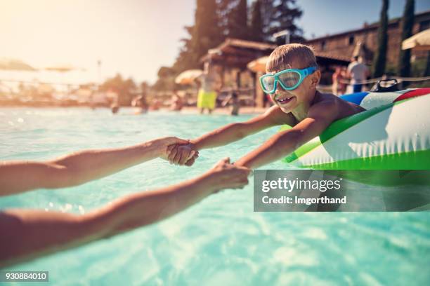 kleiner junge spielt mit mutter im schwimmbad - freibad stock-fotos und bilder