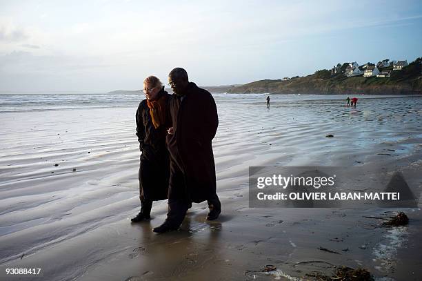 Franco-Togolese dual national politician Kofi Yamgnane walks with his wife Anne-Marie on the beach of Saint-Nic, western France, on November 14,...