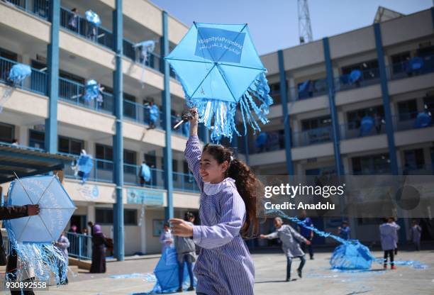 Palestinian children fly UNRWA logo printed kites outside their classrooms at a school belongs to United Nations Relief and Works Agency for...