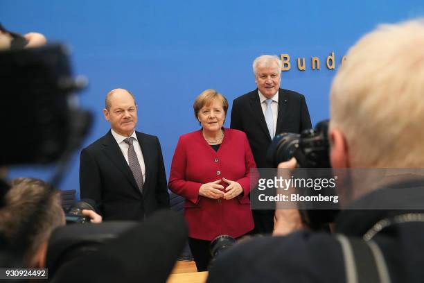 Olaf Scholz, acting chair of the Social Democratic Party and Germany's designated Finance Minister, left, Angela Merkel, Germany's chancellor and...