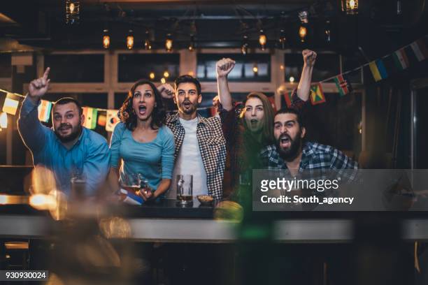 friends cheering in a pub - match sport stock pictures, royalty-free photos & images