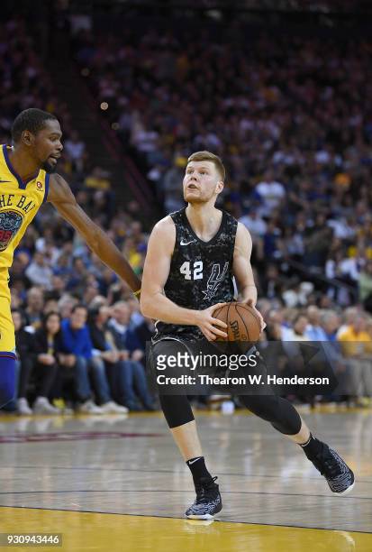 Davis Bertans of the San Antonio Spurs looks to shoot over Kevin Durant of the Golden State Warriors during an NBA basketball game at ORACLE Arena on...