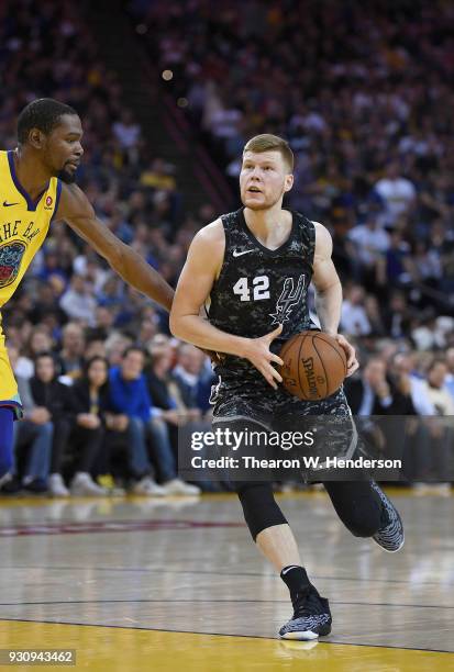 Davis Bertans of the San Antonio Spurs looks to shoot over Kevin Durant of the Golden State Warriors during an NBA basketball game at ORACLE Arena on...