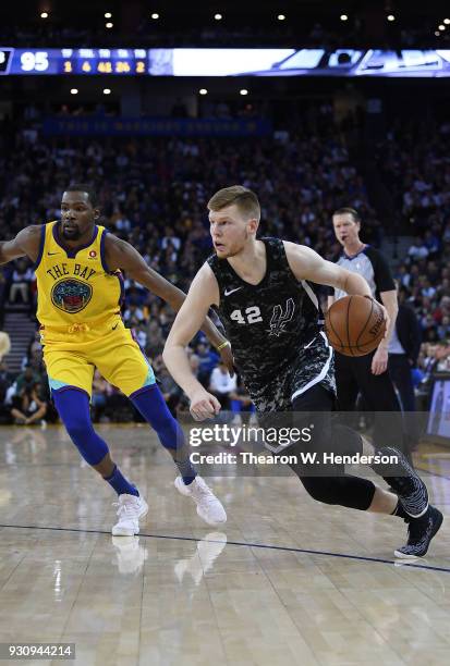 Davis Bertans of the San Antonio Spurs drives towards the baske on Kevin Durant of the Golden State Warriors during an NBA basketball game at ORACLE...