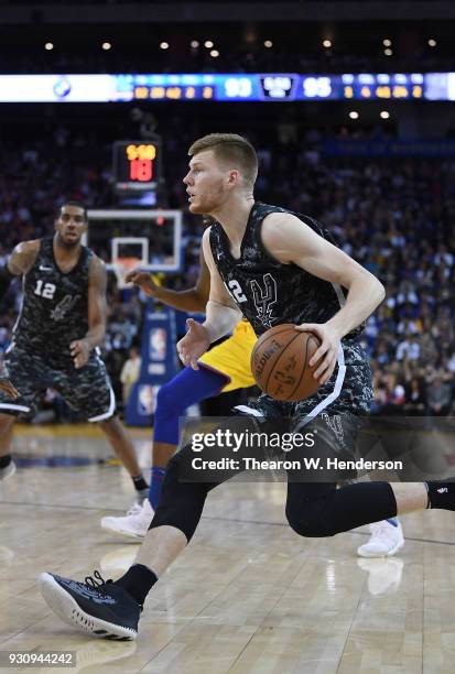 Davis Bertans of the San Antonio Spurs drives towards the baske on Kevin Durant of the Golden State Warriors during an NBA basketball game at ORACLE...