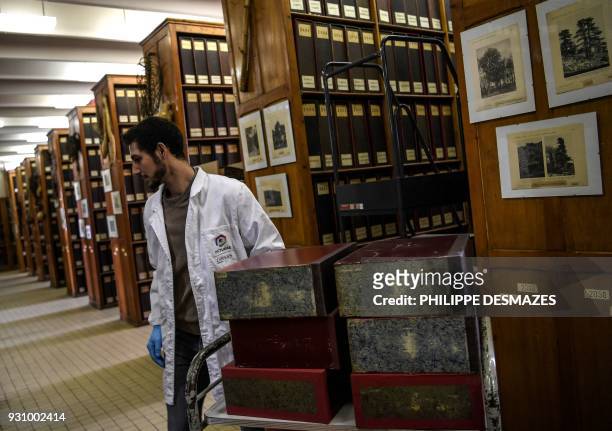 An employee puts on a cart binders containing herbarium paper sheets, to have the sheets digitalizated on March 12, 2018 at the Claude Bernard Lyon-I...
