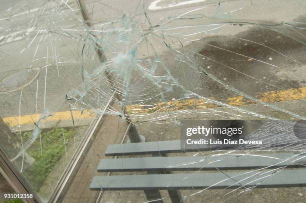 vandalised and smashed window in a bus shelter - bus shelter poster stock-fotos und bilder