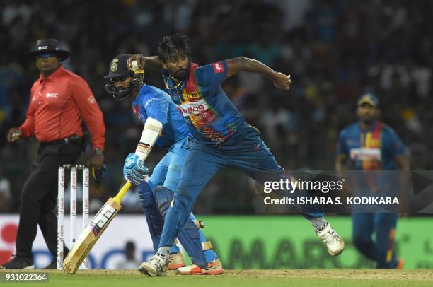 Sri Lankan cricketer Nuwan Pradeep stops ball as Indian cricketer Dinesh Karthik looks on during the fourth Twenty20 international cricket match...