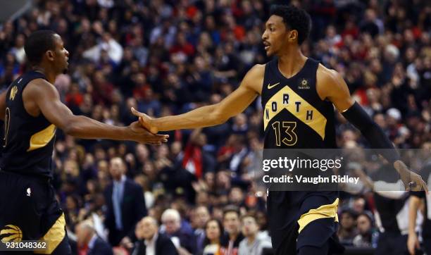 Malcolm Miller of the Toronto Raptors high fives C.J. Miles during the first half of an NBA game against the Houston Rockets at Air Canada Centre on...