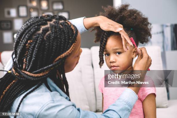 mother styling daugher's hair - marilyn nieves stock pictures, royalty-free photos & images