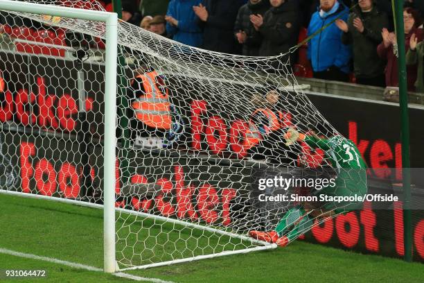 Man City goalkeeper Ederson ends up in the back of the goal net after scrambling to make a save during the Premier League match between Stoke City...