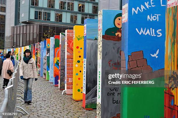 Young woman passes individually painted dominos along the former route of the wall in front of the Reichstag in Berlin on November 9 as part of the...