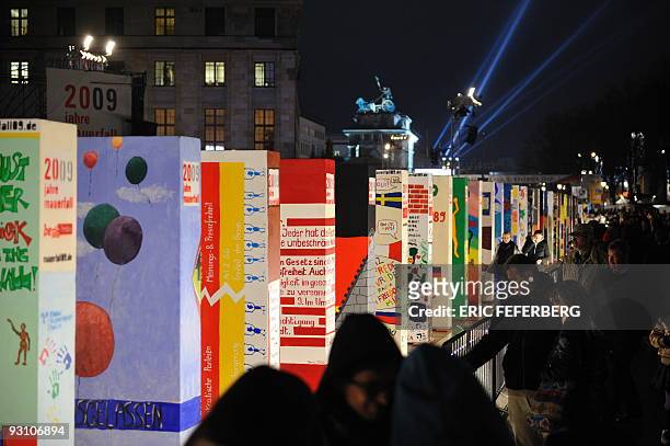 People watch the individually painted dominos set up along the former route of the wall and near the Brandenburg Gate in Berlin on November 9 as part...