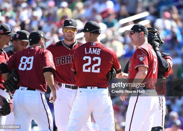 Manager Torey Lovullo of the Arizona Diamondbacks talks with new pitcher Tyler Pill as teammates Paul Goldschmidt and Jake Lamb listen in during the...
