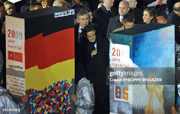 French President Nicolas Sarkozy watch as children prepare to push the final domino pieces in front of the Brandenburg Gate in Berlin November 9...