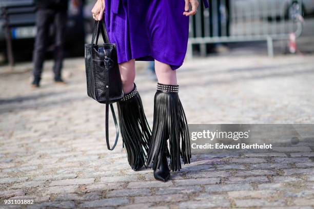 Guest wears dark violet skirt, a black tote bag, large fringe studded hem black boots, during Paris Fashion Week Womenswear Fall/Winter 2018/2019, on...