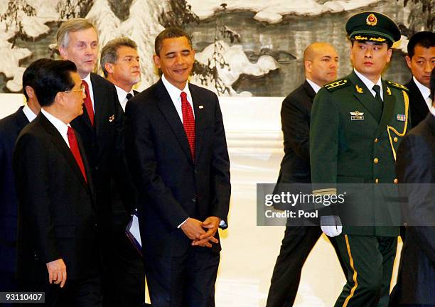 President Barack Obama reacts as he talks with Chinese President Hu Jintao as they arrive with officials at an official welcoming dinner in the Great...