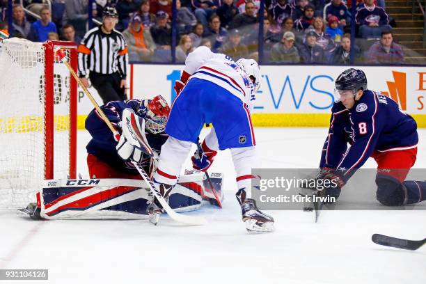 Zach Werenski of the Columbus Blue Jackets attempts to control the puck as Brendan Gallagher of the Montreal Canadiens fires the puck wide of Sergei...