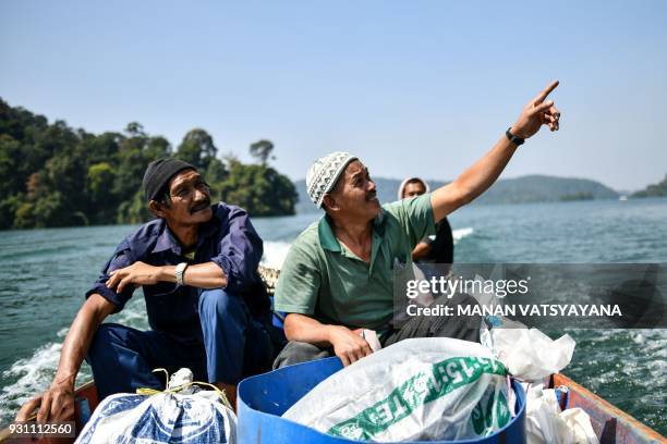 This photograph taken on February 11, 2018 shows traditional Malaysian honey hunters Zaini Abdul Hamid pointing to Abdul Samad Ahmad bee-nests atop...