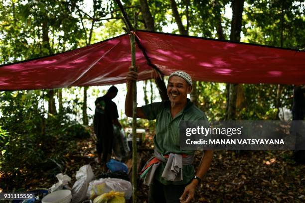 This photograph taken on February 11, 2018 shows traditional Malaysian honey hunters Zaini Abdul Hamid smiling after setting up a base tent to...