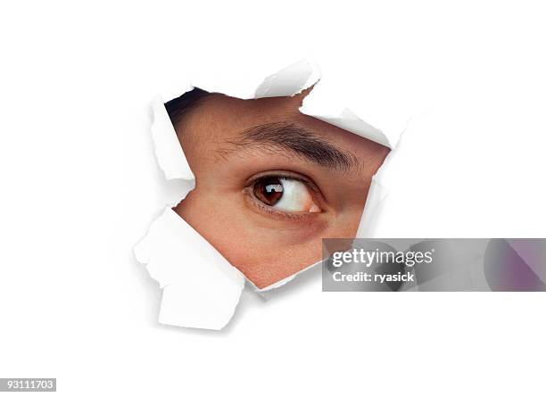 male eye staring out of hole of ripped white paper - peeping holes stock pictures, royalty-free photos & images