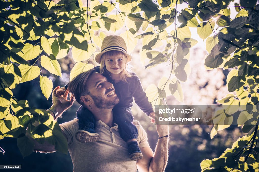 Young carefree father and son enjoying among tree branches in springtime.