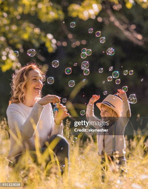 unbeschwerte mutter und ihr kleiner sohn spaß im frühling während der seifenblasen. - bubbles happy stock-fotos und bilder