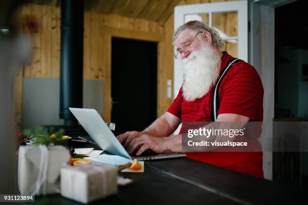 santa claus in his living room using laptop - santa beard stock pictures, royalty-free photos & images