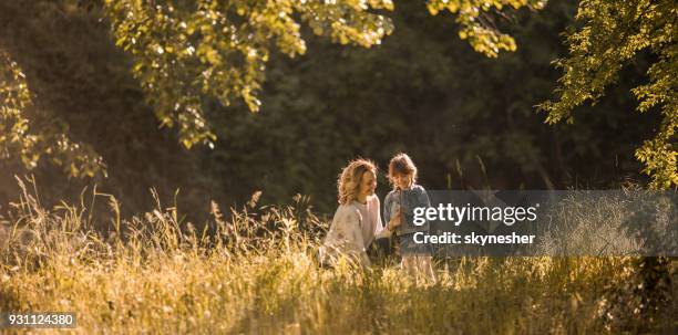 happy mother and her small girl picking flowers during springtime in nature. - family panoramic stock pictures, royalty-free photos & images