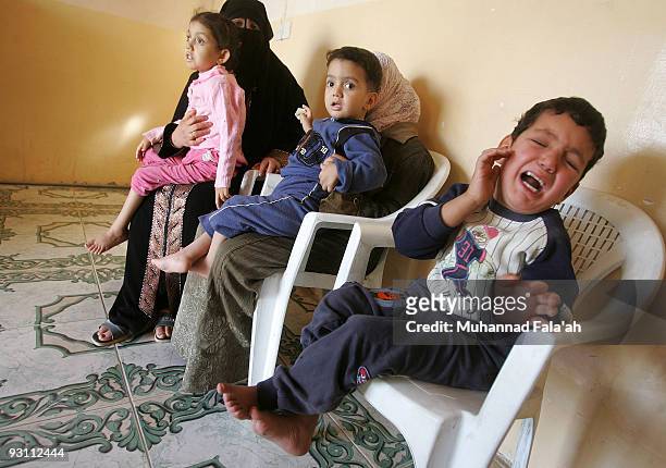 Ammar Yasir, age 5 years old, Mustafa Yasir, age 3 years old held by his cousin, Mariam Yasir, age 6 years old, and their mother are seen through a...