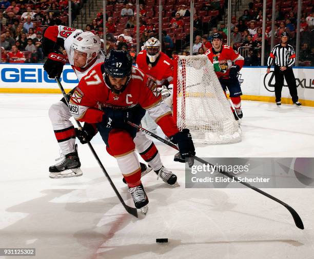 Derek MacKenzie of the Florida Panthers skates for possession against Max McCormick of the Ottawa Senators at the BB&T Center on March 12, 2018 in...