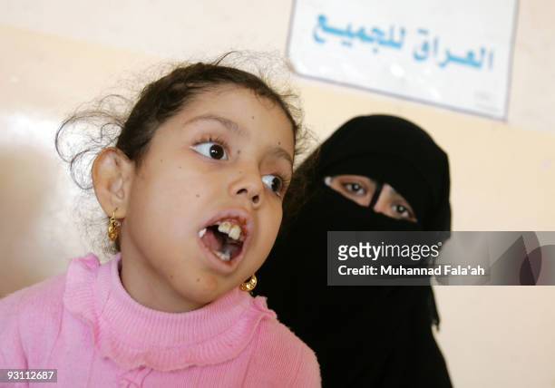 Mariam Yasir , age 6 years old, who suffers from a birth defect is held by her mother as a sign reading in Arabic is seen on November 12, 2009 in the...