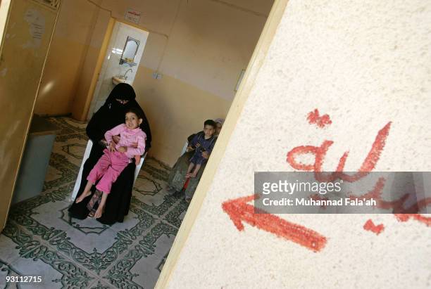 Mariam Yasir , age 6 years old, who suffers from a birth defect is held by her mother as the Arabic word is seen on November 12, 2009 at the Iraqi...