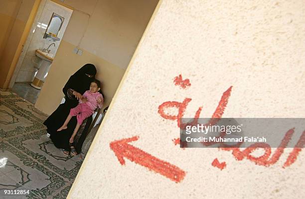 Mariam Yasir , age 6 years old, who suffers from a birth defect is held by her mother as the Arabic word is pictured on November 12, 2009 at the...