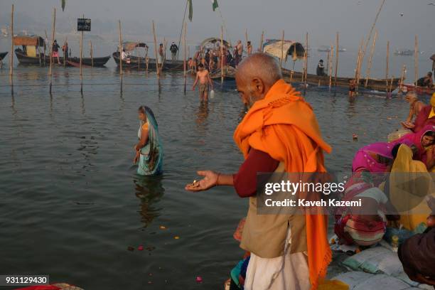 An Indian Hindu devotee man offers prayers by lighting a small candle on the banks of Sangam which is the point of confluence of River Ganga, Yamuna...