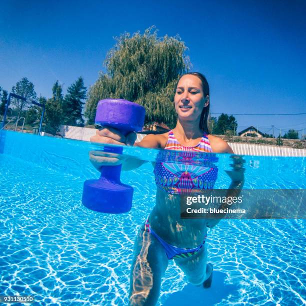 frau, die das training mit hanteln im schwimmbad - hantel stock-fotos und bilder