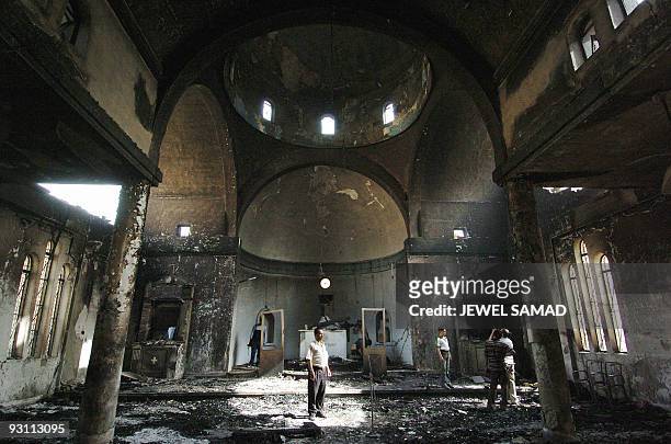 Iraqi people gather to witness the damage inside a church following an explosion in Baghdad, 16 October 2004. Bombs exploded near five churches...