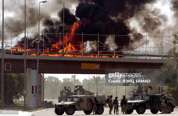 Heavy smoke billows from a burned US Humvee and a civilian car at a bridge that leads to Baghdad's International Airport 18 September 2004. A US...