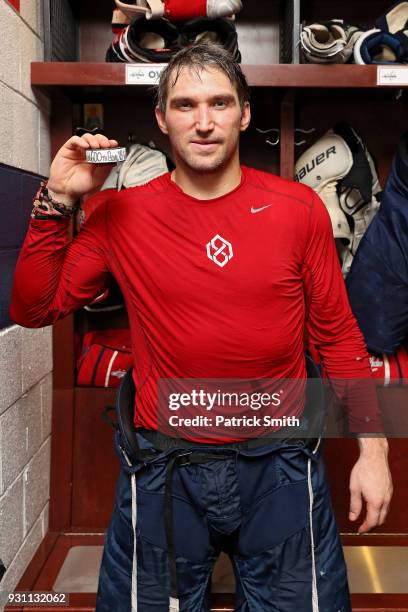 Alex Ovechkin of the Washington Capitals poses with the puck commemorating his 600th career goal in which he scored during the second period against...