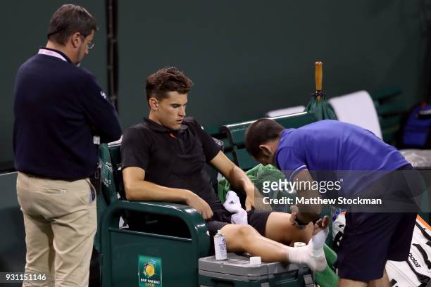Dominic Thiem of Austria receives treatment from ATP trainer David Pires after losing the second set to Pablo Cuevas of Uraguay during the BNP...