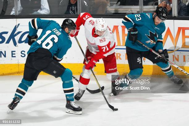 Dylan Larkin of the Detroit Red Wings keeps the puck away from Eric Fehr and Barclay Goodrow of the San Jose Sharks at SAP Center on March 12, 2018...