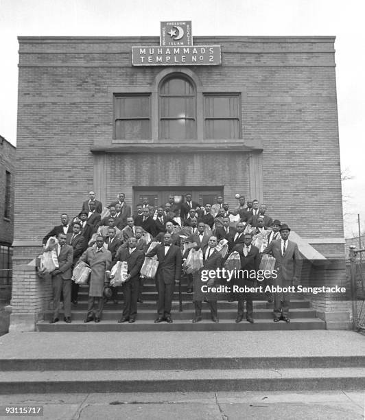 Nation of Islam members stand on the steps of Muhammad's Temple No. 2 with bundles of the NoI newspaper, Muhammad Speaks, under their arms, Chicago,...