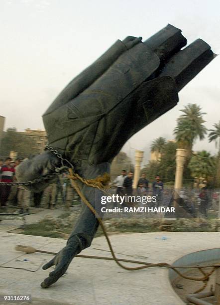 Statue of Iraqi President Saddam Hussein falls after it was pulled down by a US Marine vehicle in Baghdad's al-Fardous square 09 April 2003. Iraqis...