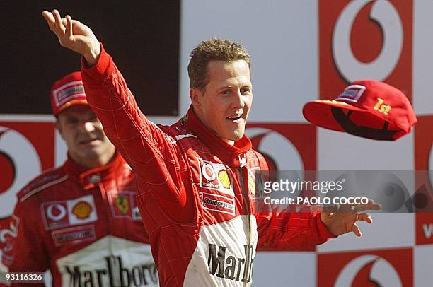German Ferrari driver Michael Schumacher , flanked by his teammate Brazilian driver Rubens Barrichello, throws his cap from the podium of the Monza...